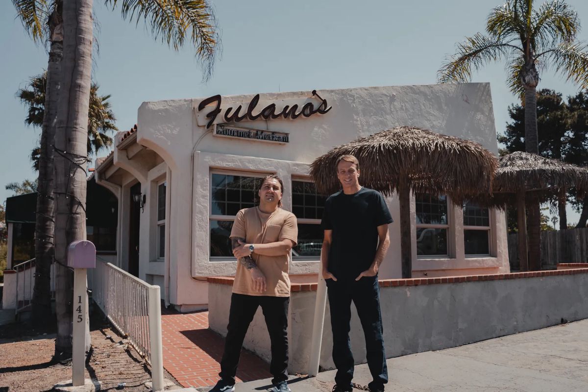 Andrew Bachelier and Tony Hawk stand in front of a restaurant.