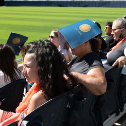 Families and loved ones shade themselves from the sun with graduation programs at Whitney M. Young Magnet High School’s graduation ceremony. 