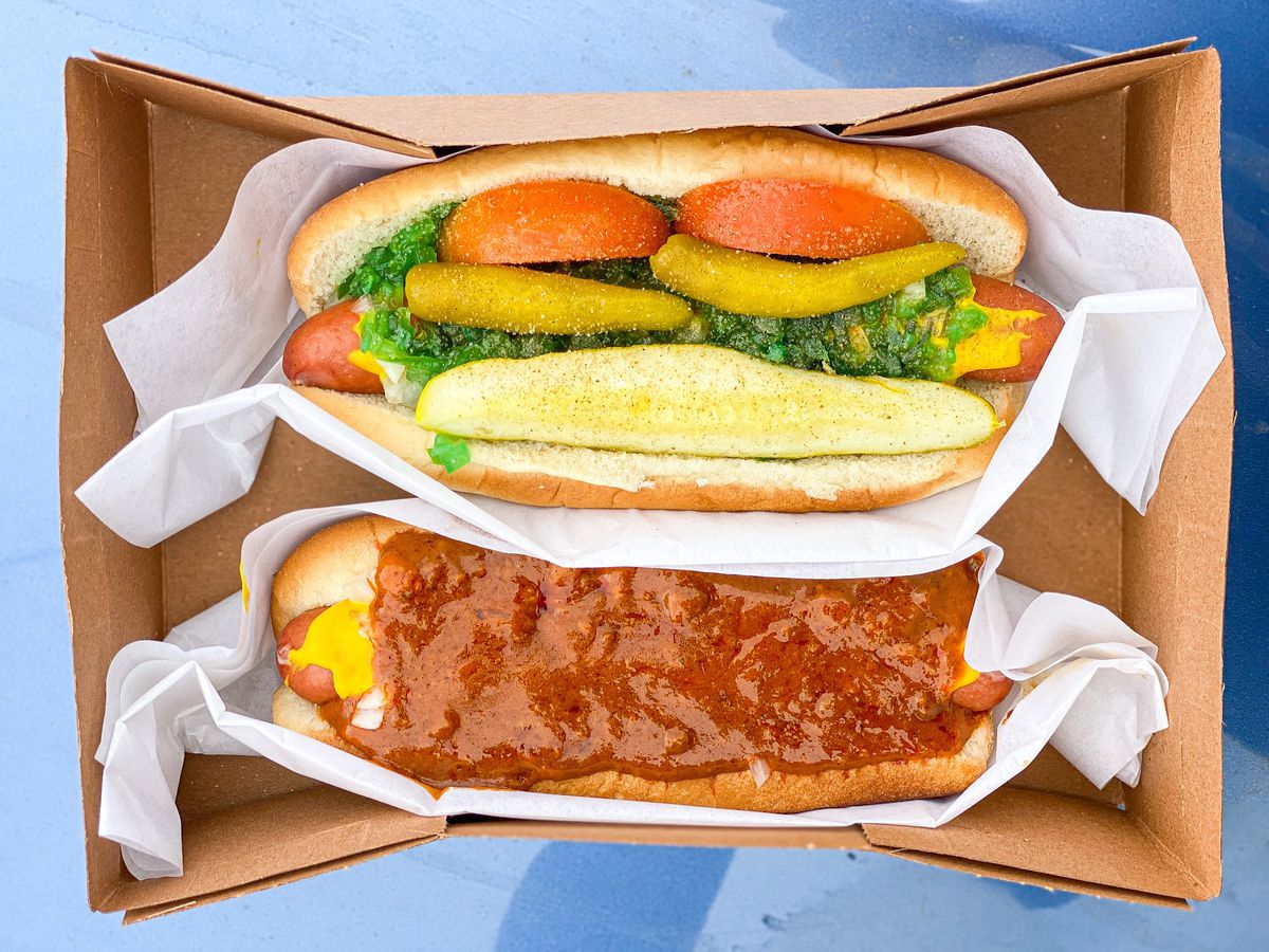 An overhead shot of a box of hot dogs, including a fully dressed Chicago option.