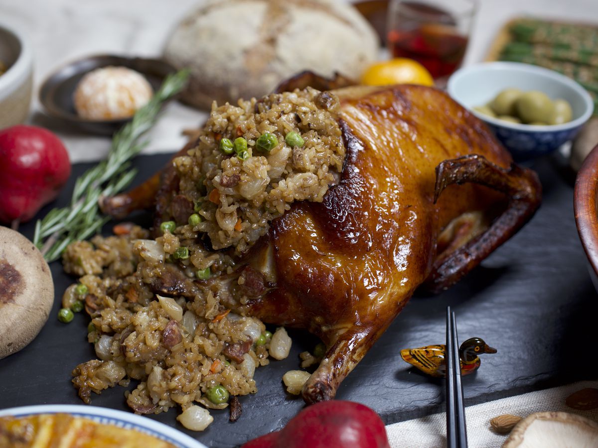 A roasted duck stuffed with sticky rice laid out on a holiday-decorated table.