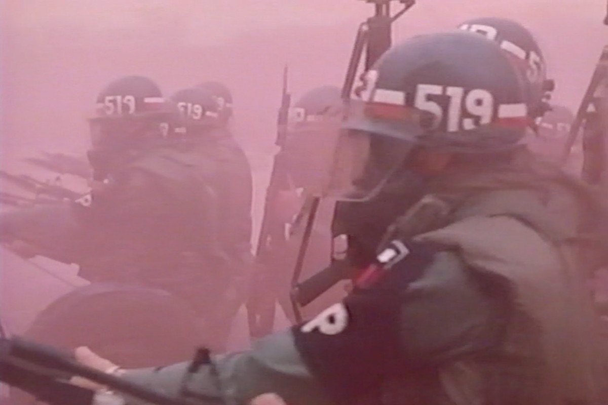 Archival footage of men in riot gear.