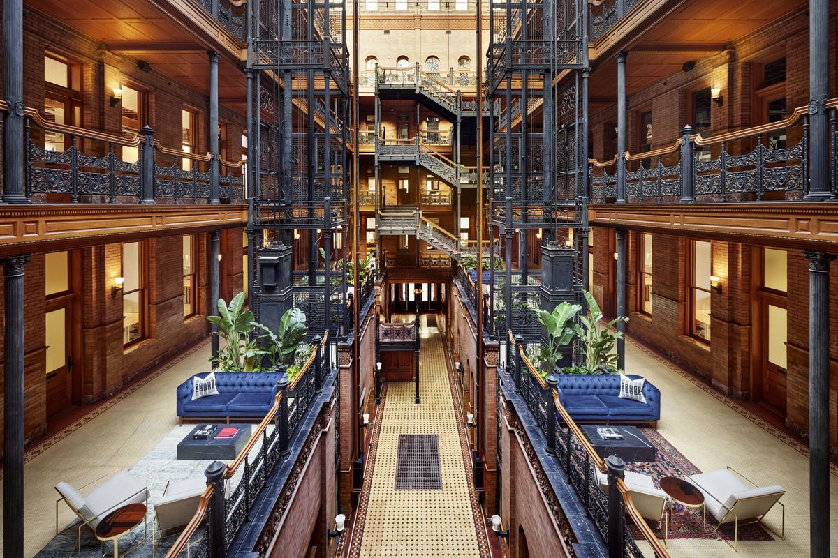 An overhead view of a historic wrought iron and wood building with multiple open floors and sunlight streaming in.
