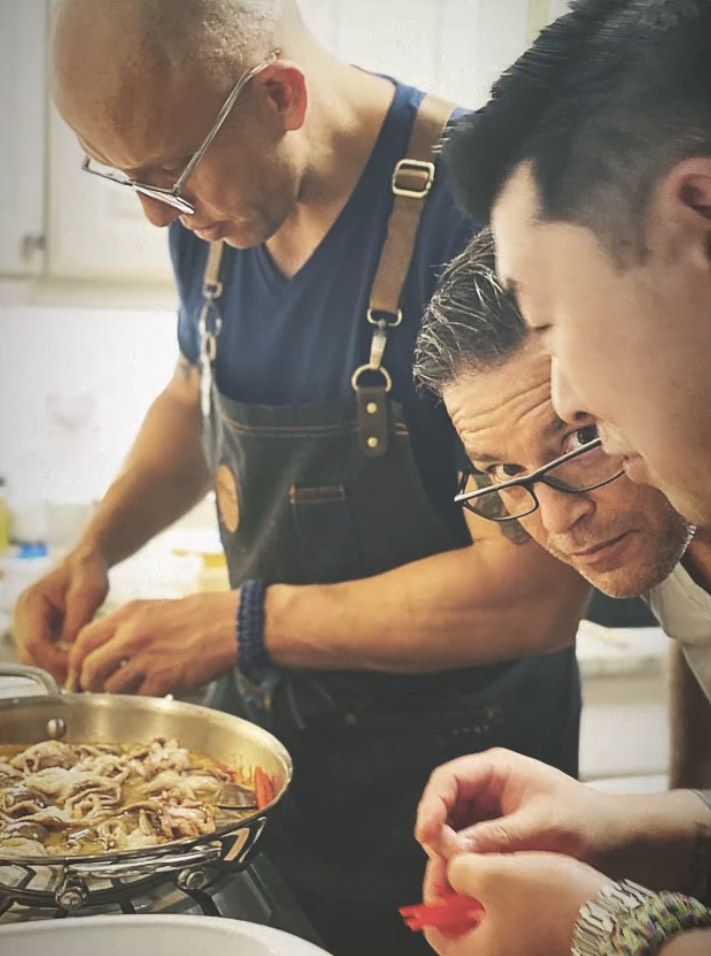 Ronaldo Linares, Christopher Daugherty, and Young Cho (left to right) hovering over a counter while preparing food.