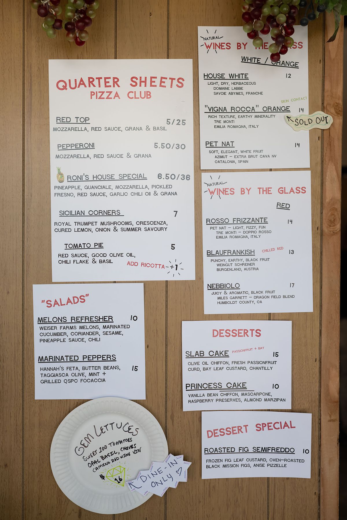 Printed menus hanging on a wooden wall.
