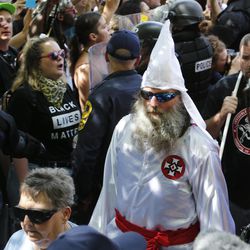 This July 8, 2017 photo shows members of the KKK escorted by police past a large group of protesters during a KKK rally in Charlottesville, Va.  Some white Southerners are again advocating for what the Confederacy tried and failed to do in the 1860s: secession from the Union. So-called Southern nationalists are within the group of demonstrators who are fighting the removal of Confederate monuments around the South. They say it’s time for Southern states to secede again and become independent of the United States..
