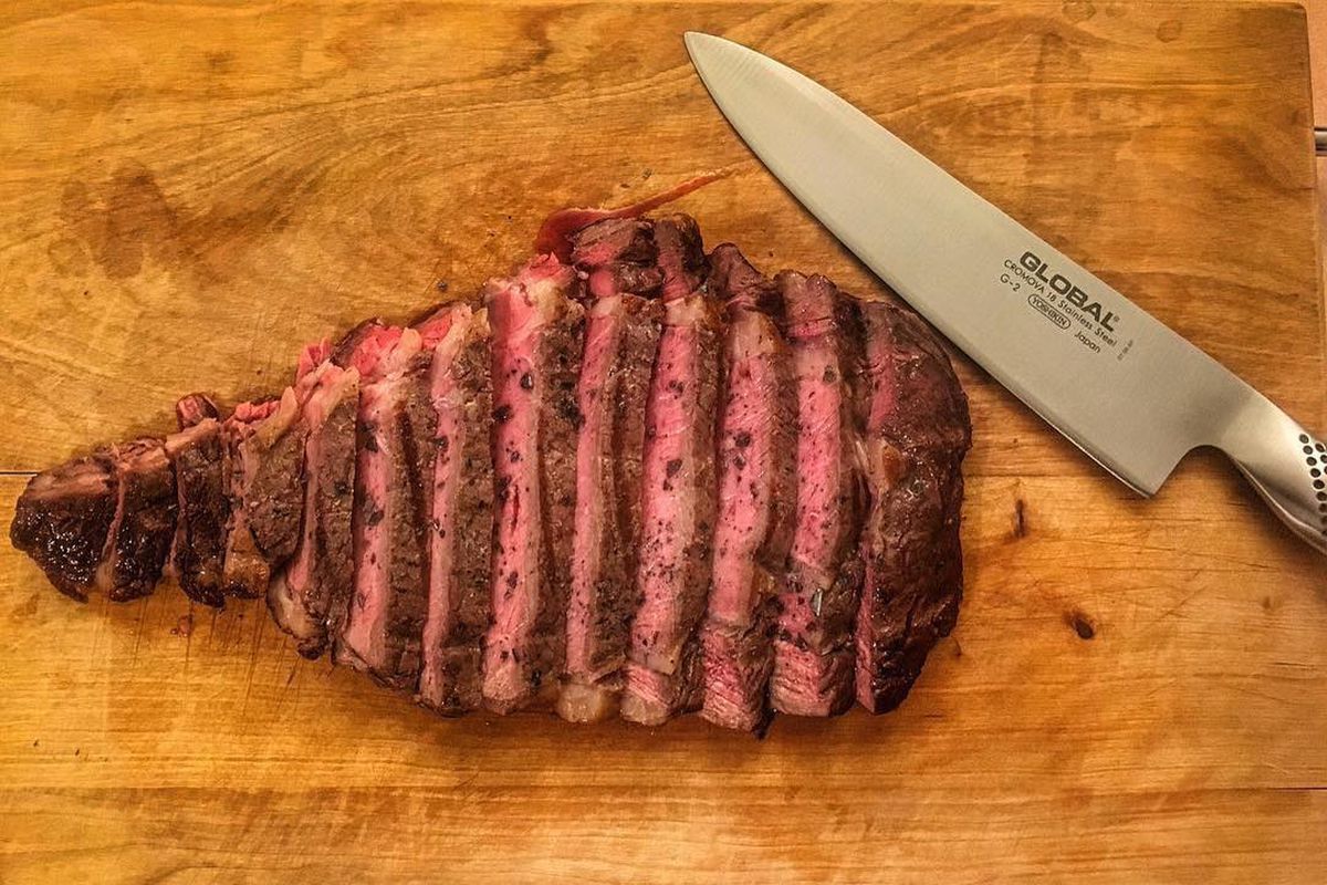 Chef’s knife with cut steak on cutting board