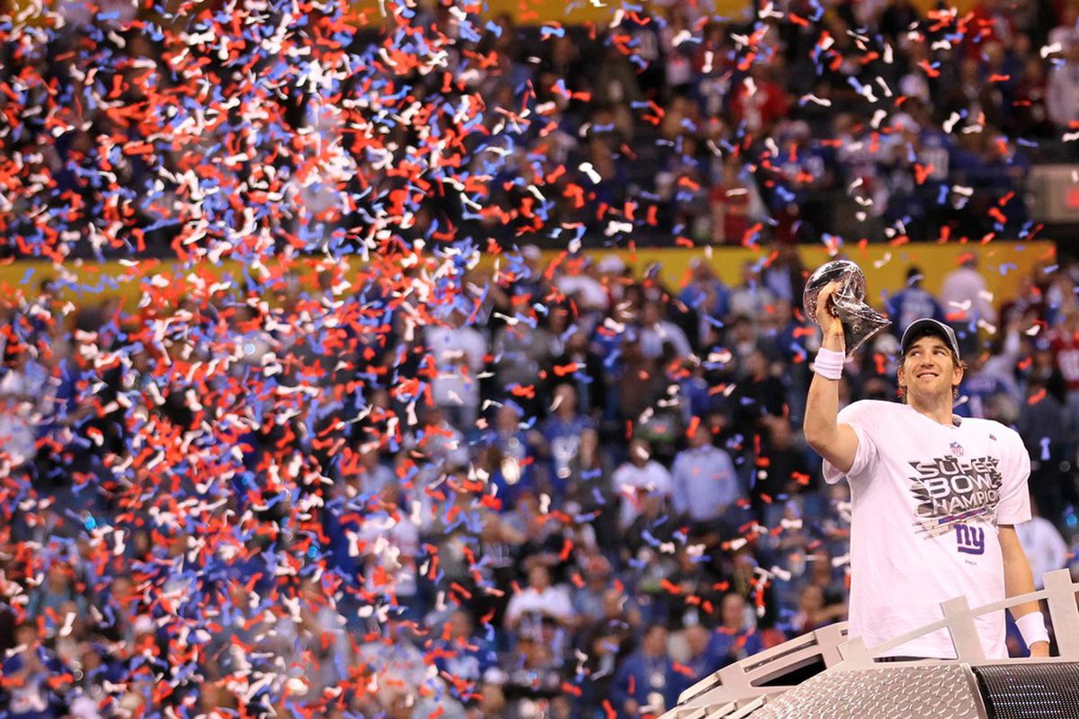 Super Bowl MVP Eli Manning hoists the Lombardi Trophy (US Presswire)