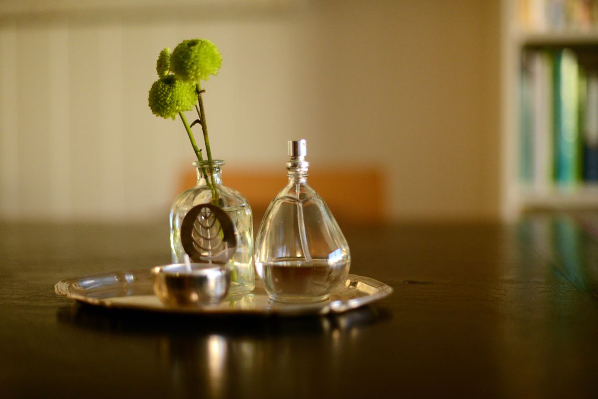 green flowers in a small vase and a perfume bottle