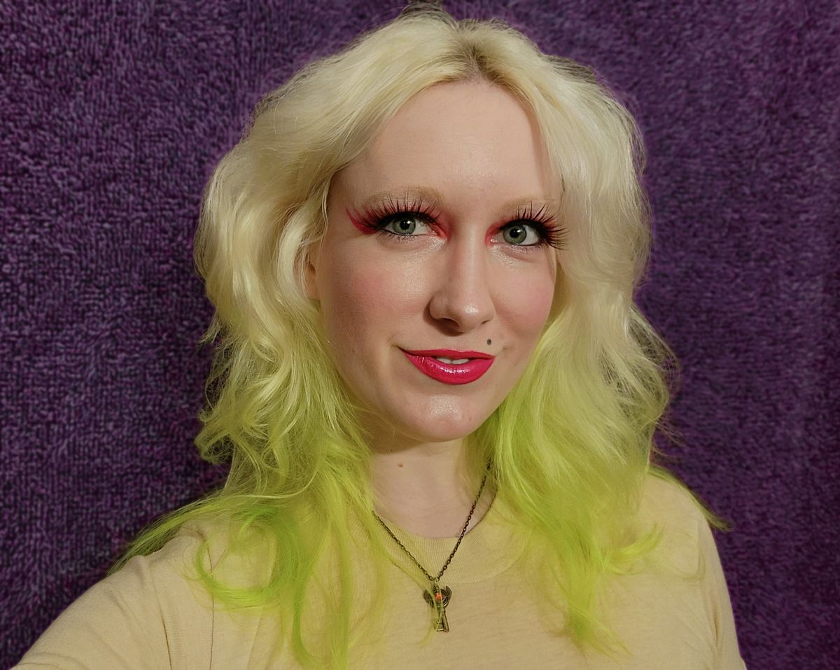 The author wearing everyday makeup, with pink eyeliner, and blonde hair with lime green tips