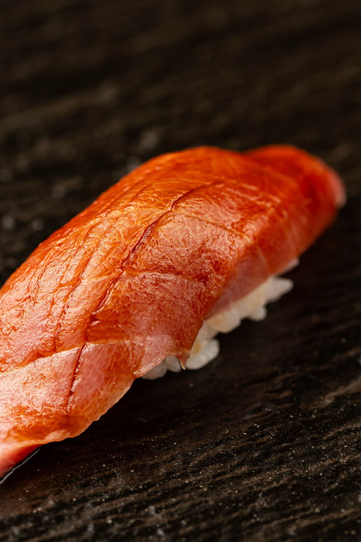 A nigiri course at Sushi Note Omakase, set against a dark wood background.