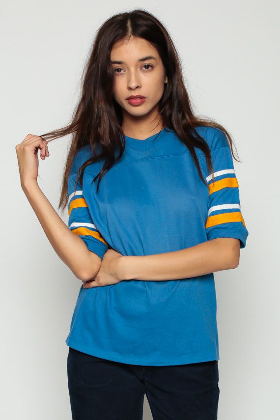 A woman models a blue T-shirt with white and yellow stripes on the sleeves