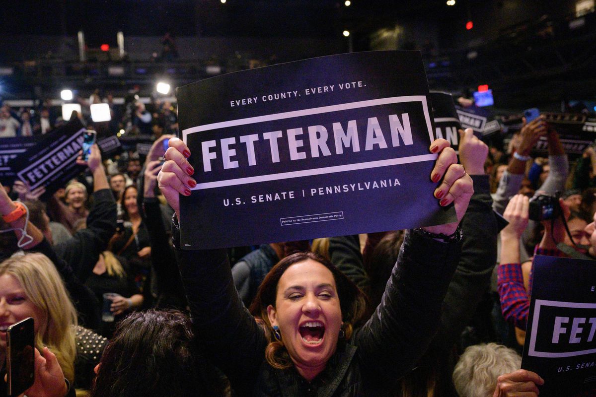 A person in a crowd holds up a sign reading “Fetterman U.S. Senate.”