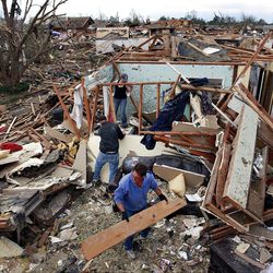 Jimmy Hodges helps Chad Heltcel and his wife, Cassidi, salvage the wreckage of the Heltcels' home, which was destroyed in Monday's storm.    