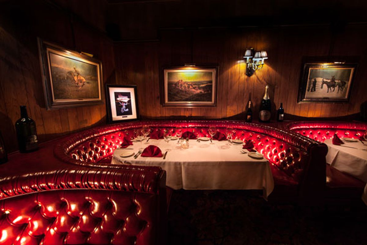 A restaurant interior with red leather booths and photos on the walls.