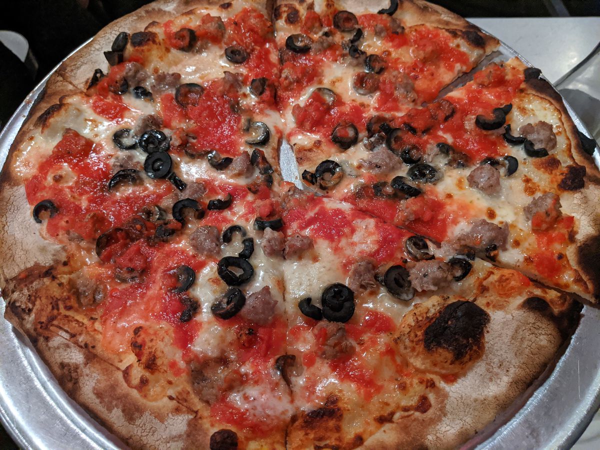 A pizza with sausage and black olives and red sauce