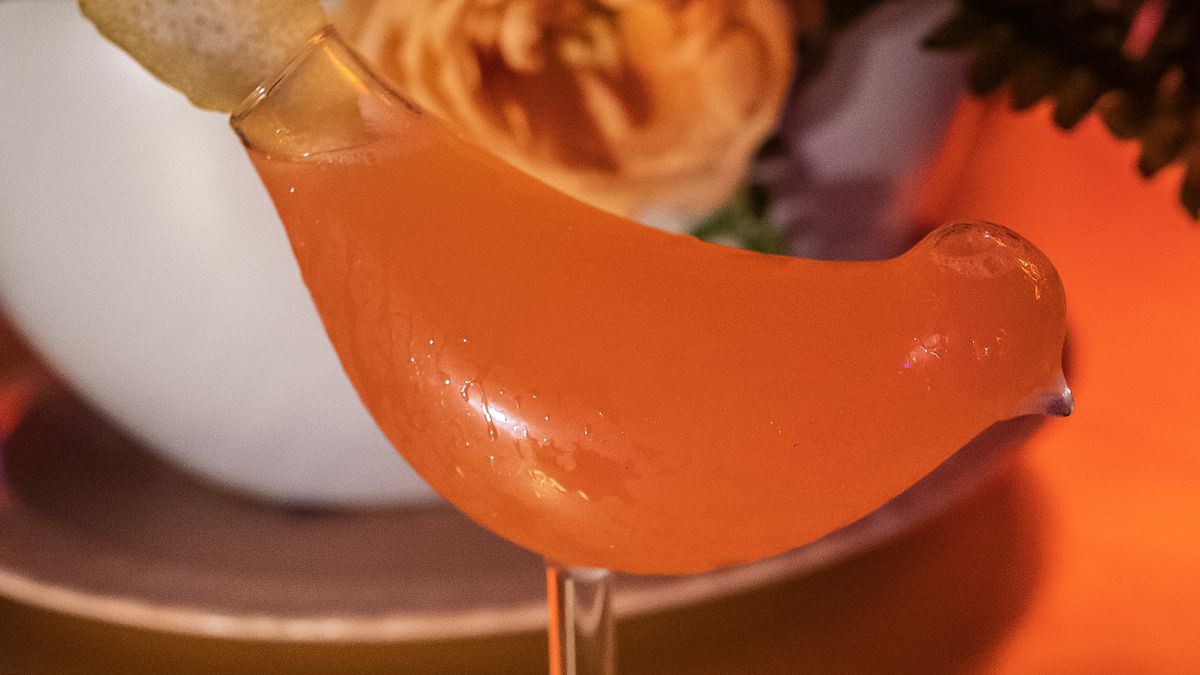 A bird-shaped glass with orange liquid.