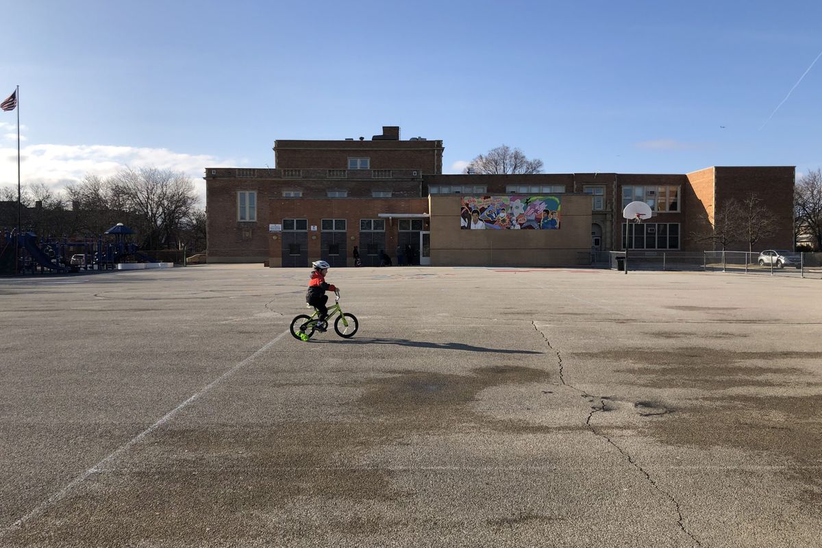 A child rides a bicycle at a shuttered Chicago public school the first week that campuses closed.