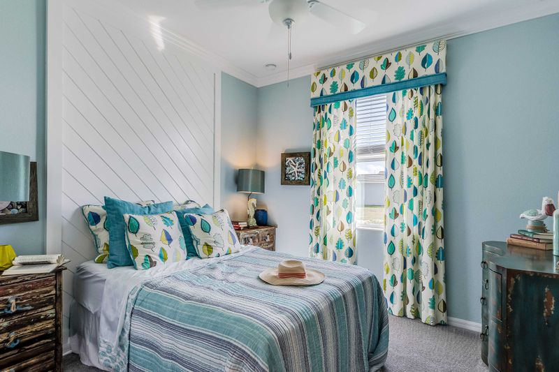 A costal bedroom with a diagonal shiplap wall feature behind the bed.