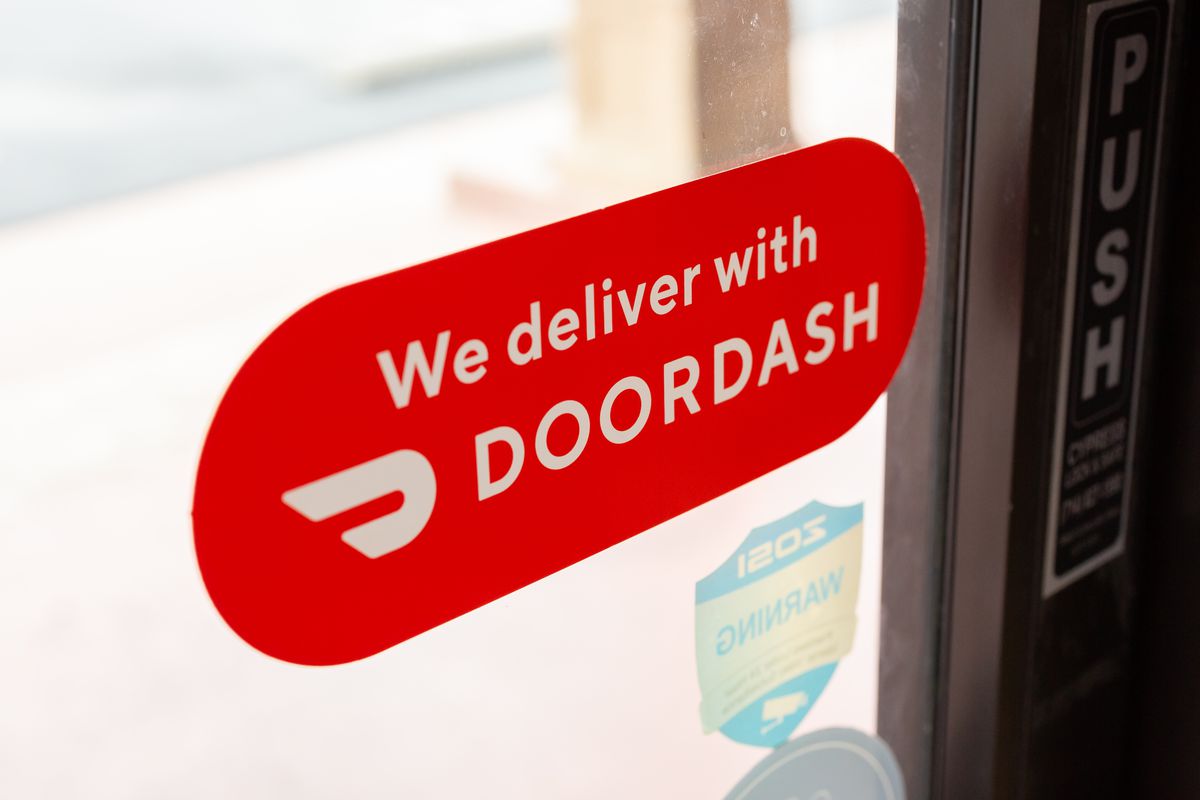A sticker on a restaurant front door says “We deliver with DoorDash.”