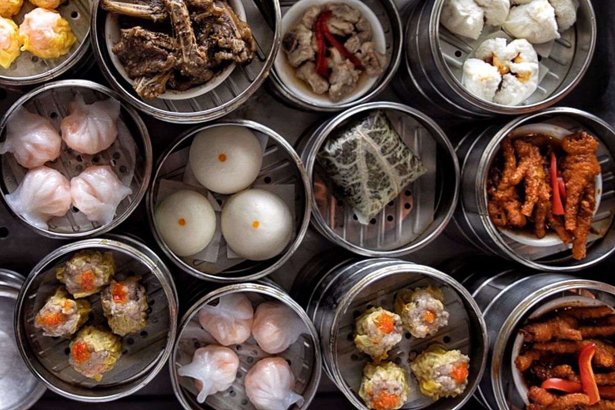 Round serving tins willed with dumplings and dim sum items. 