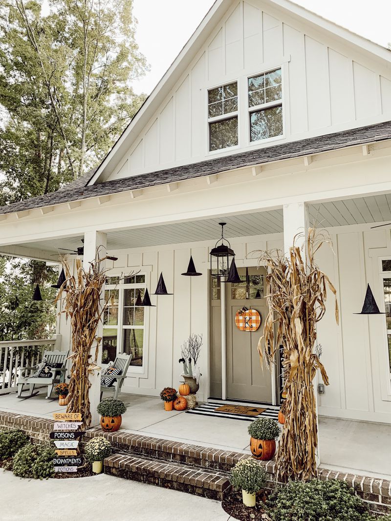 A not so spooky Halloween porch with floating hats, corn stalks and pumpkins. 
