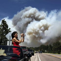 Colorado Springs resident Yolette Baca takes a photo of the wildfire in the Black Forest area north of Colorado Springs, Colo., on Wednesday, June 12, 2013. The number of houses destroyed by the Black Forest fire could grow to around 100, and authorities fear it's possible that some people who stayed behind might have died. 