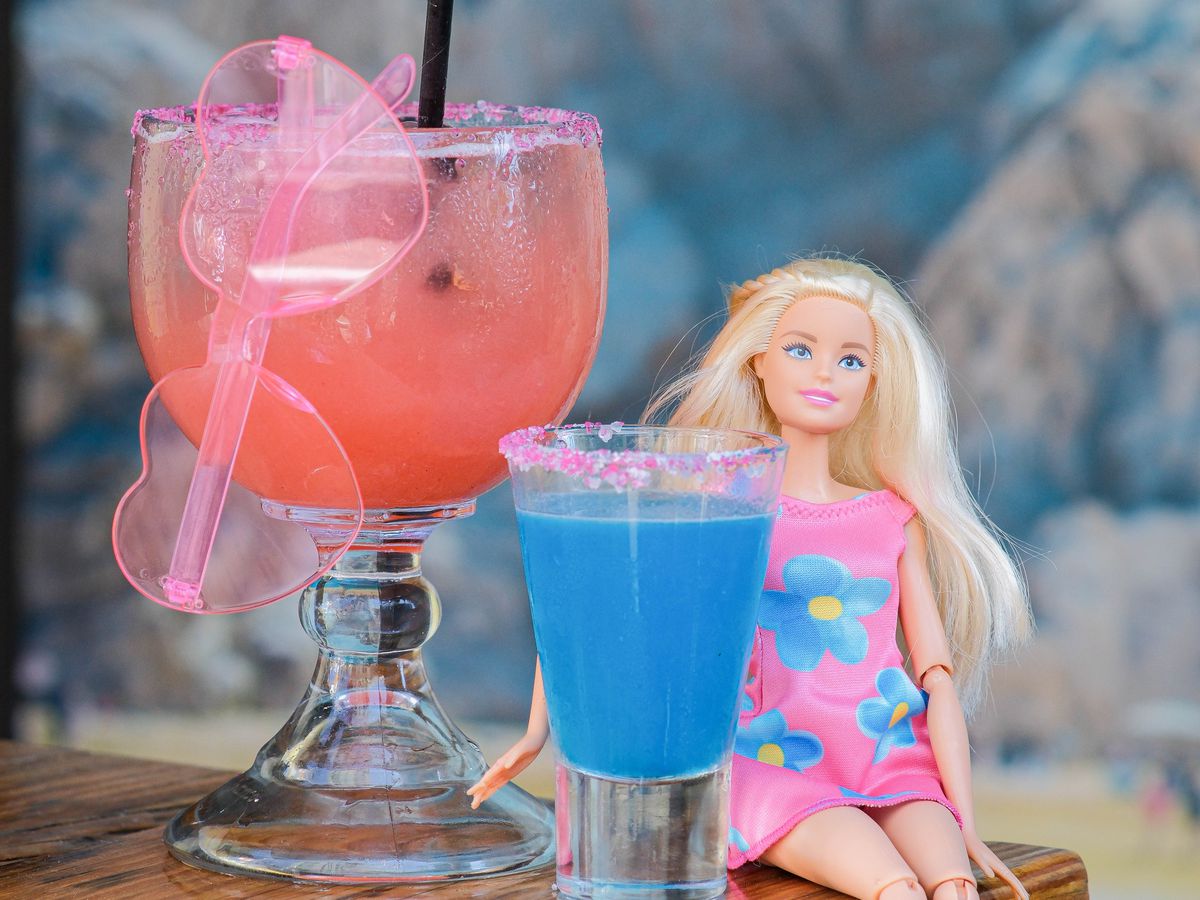 A Barbie doll next to colorful cocktails.