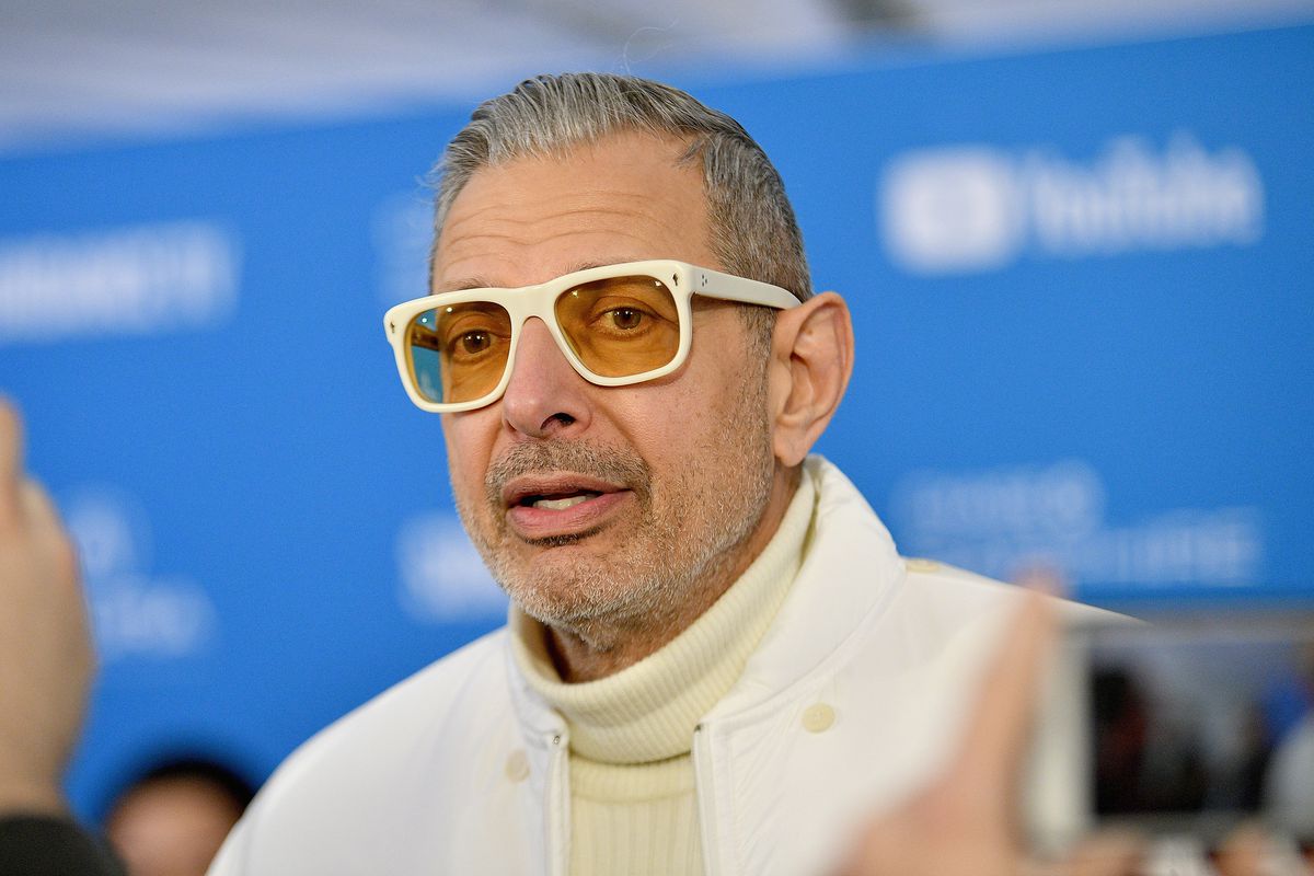 Jeff Goldblum wears white-framed glasses at a media event
