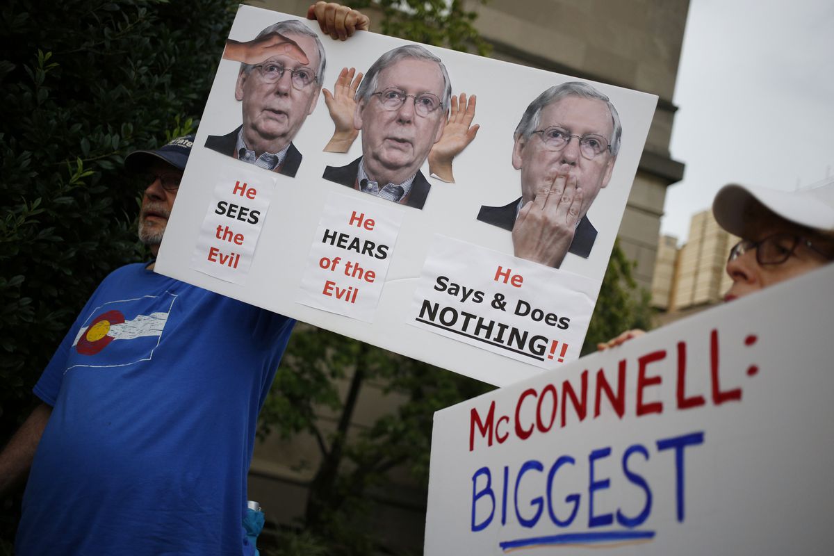 Protesters holding signs outside of Mitch McConnell’s office after two mass shootings in August.