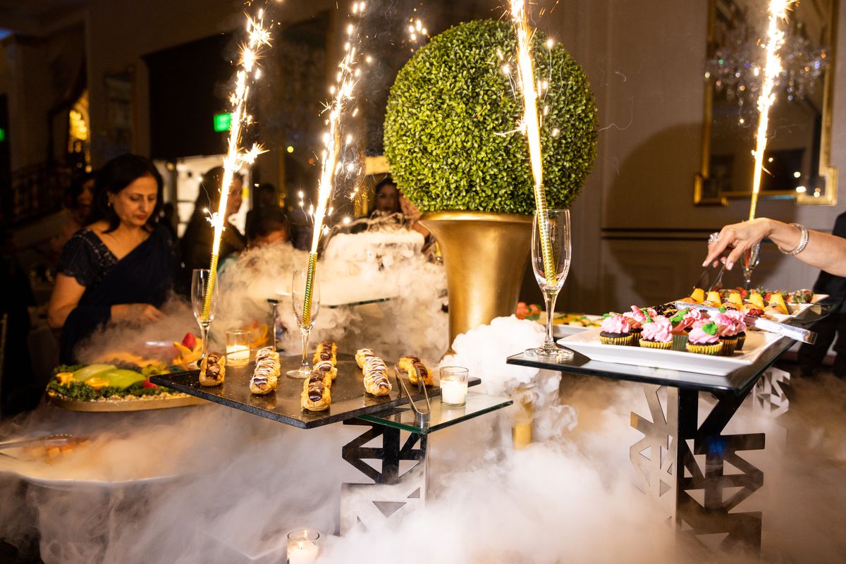 A wedding dessert table set-up that includes fog and sparklers.
