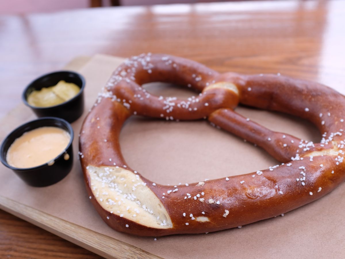 A large pretzel served on butcher paper with dipping sauces.