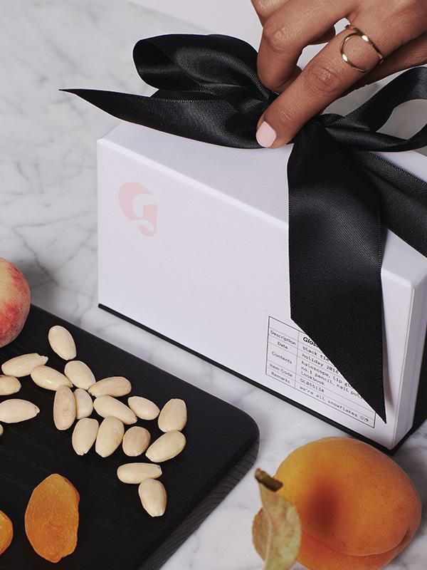 Glossier's Black Tie box pictured next to fruit and nuts.