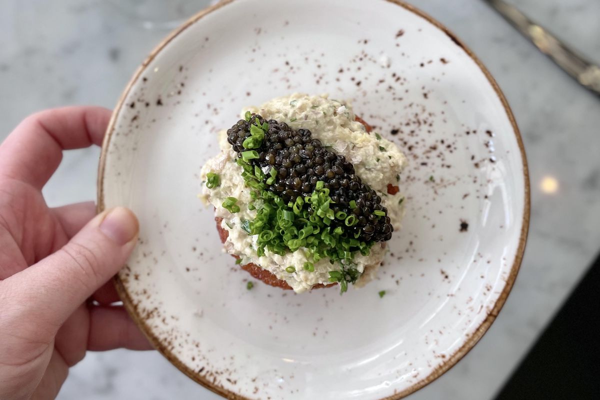 A photo of caviar on a little piece of bread.