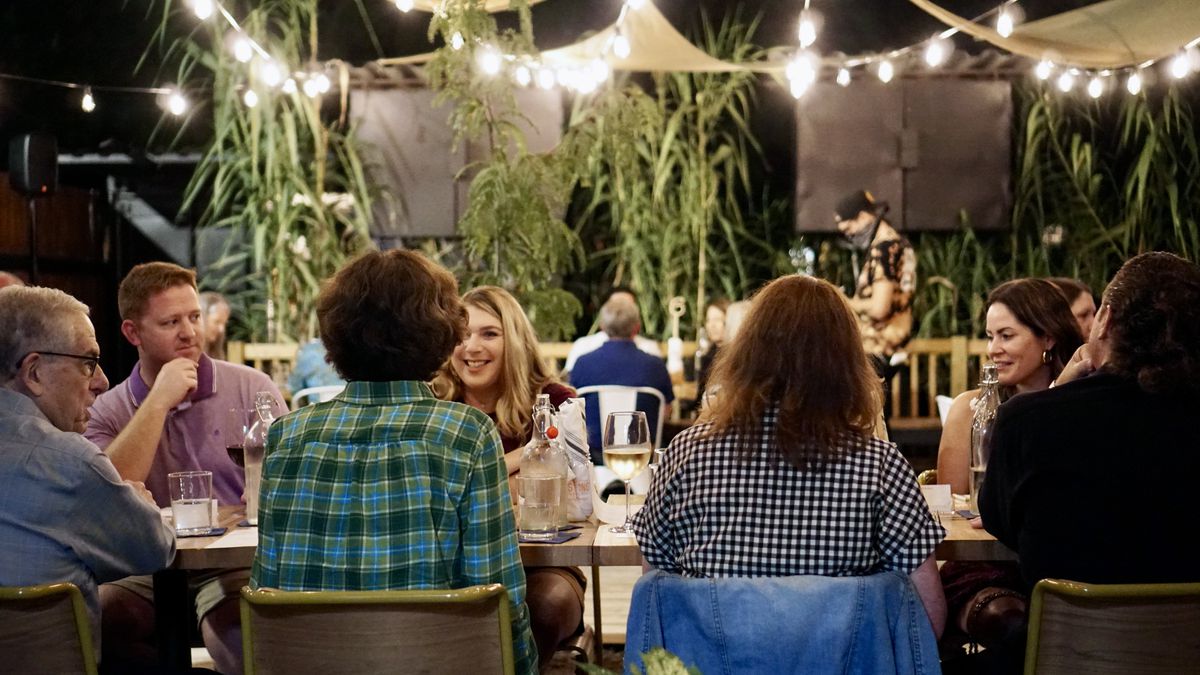 Members dine on patio seating beneath string lights.