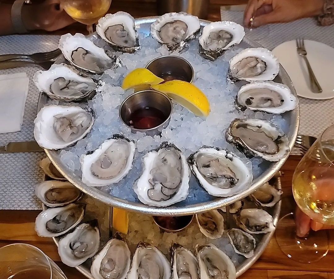 A two-level tower of iced raw oysters on the half shell.