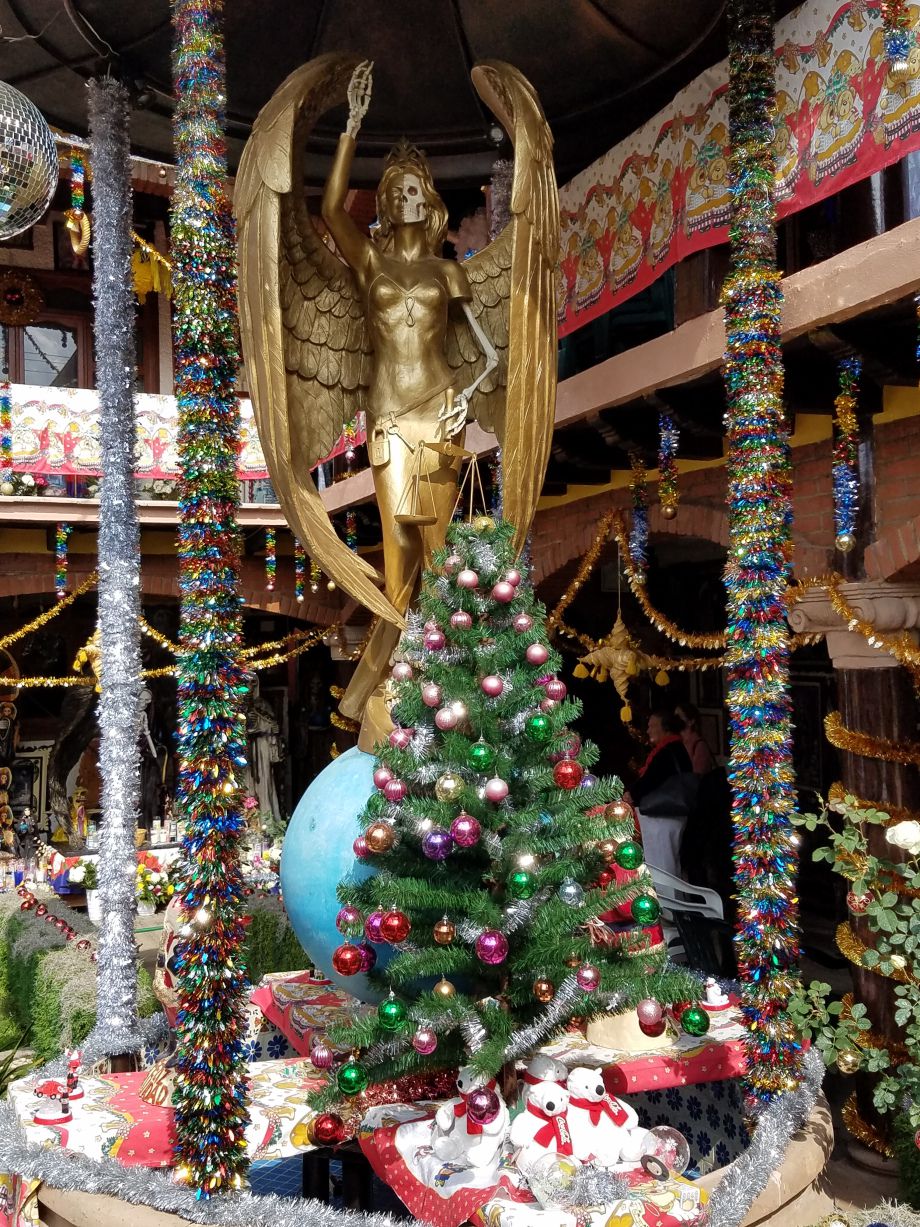 A Christmas scene featuring a decorated tree a gold-plated Sante Muerte figure dressed in a bikini.