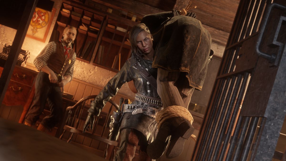 Red Dead Online - a bounty hunter carries a hog tied criminal over her shoulder on the way to a jail cell.