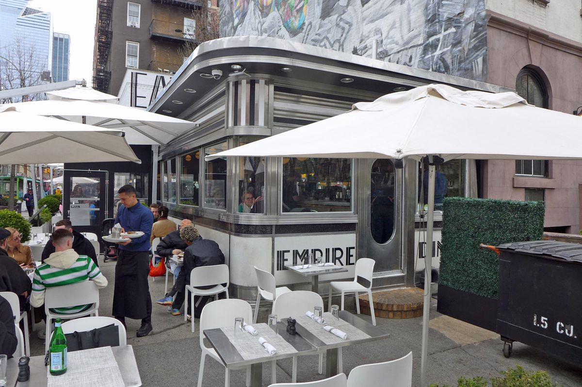 A streamlined diner with outdoor tables and umbrellas.