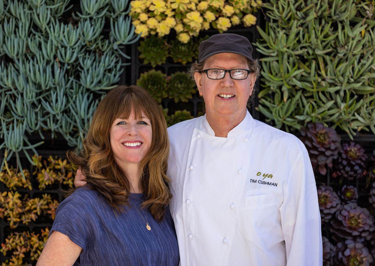 A red-haired woman stands next to a man with glasses in a chef’s coat.