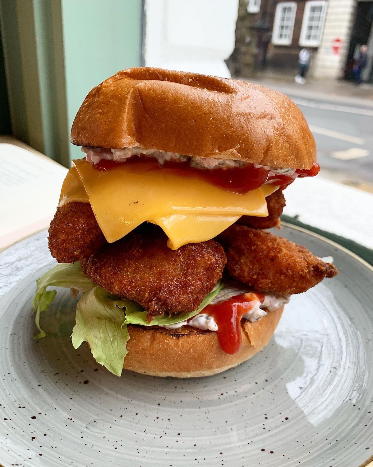 A stacked fish goujon sandwich on a ceramic plate 