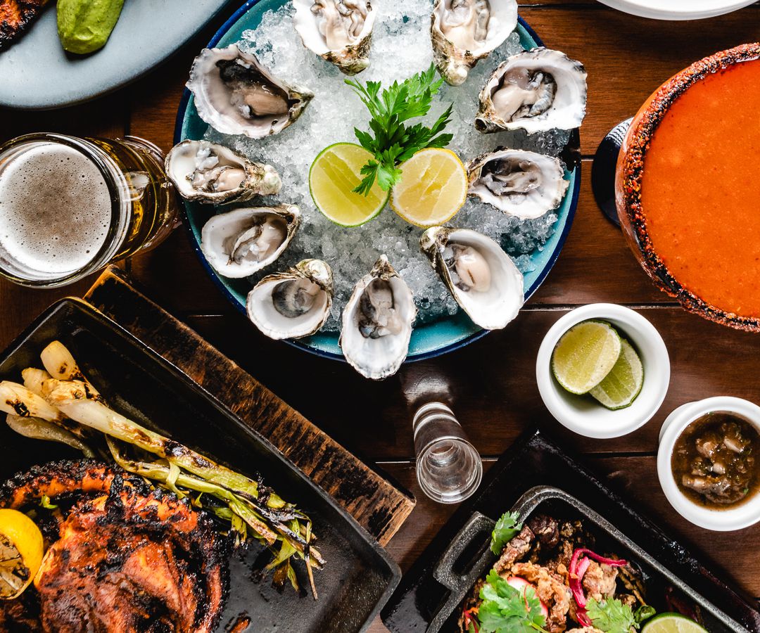 A platter of raw oysters with grilled seafood and other dishes.