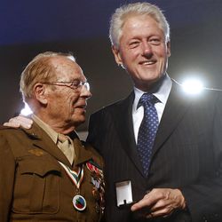 Former President Bill Clinton, right, presents World War II Army veteran Scottie Ooton, a member of the 84th Infantry Division which liberated Hannover-Ahlem concentration camp, with for the 20th anniversary pin of the United States Holocaust Memorial Museum in Washington, Monday, April 29, 2013. (AP Photo/Charles Dharapak)