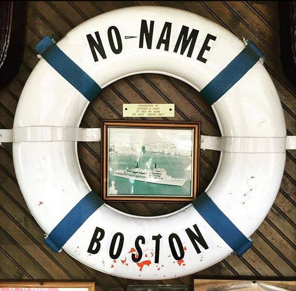 A buoy with the words “No Name” and a photograph of a boat adorn a wall at No Name Restaurant