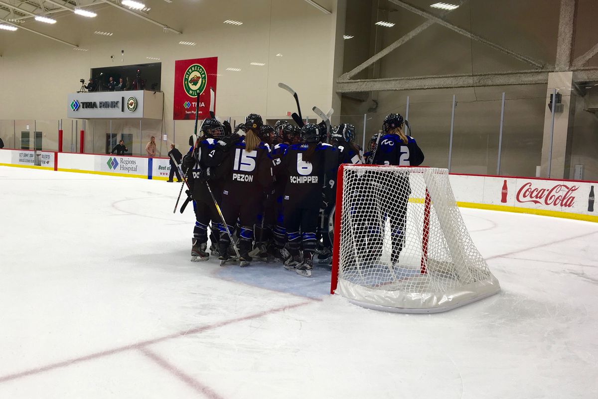 The Minnesota Whitecaps all hugging their goaltender after winning a game on the ice.