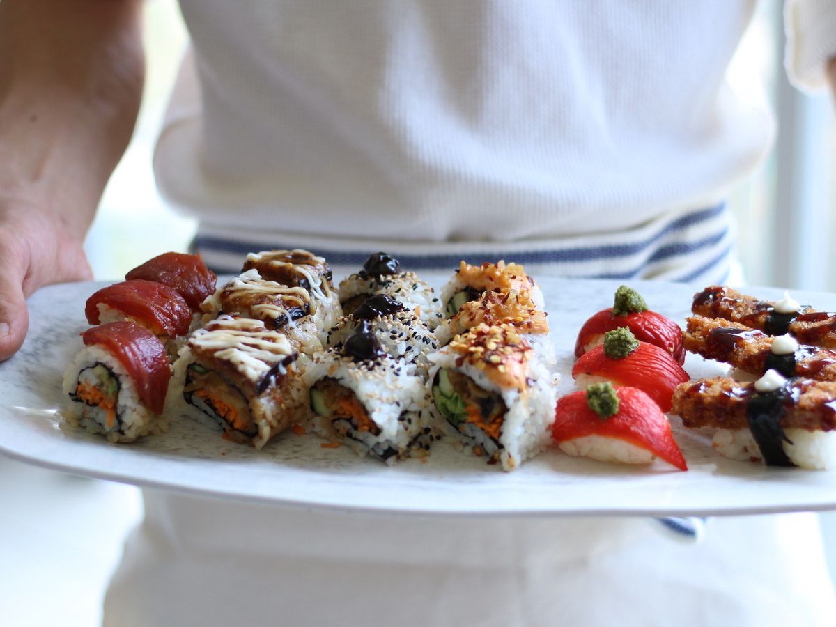 A server holds a tray of vegan sushi.