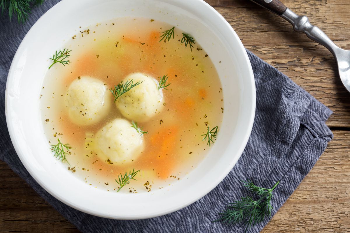 homemade Matzo Ball soup with vegetables on wooden, top view 