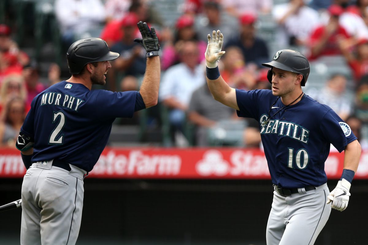 Tom Murphy #2 of the Seattle Mariners high-fives Jarred Kelenic #10 of the Seattle Mariners after Kelenic hit a home run in the seventh inning against the Los Angeles Angels at Angel Stadium of Anaheim on September 26, 2021 in Anaheim, California.