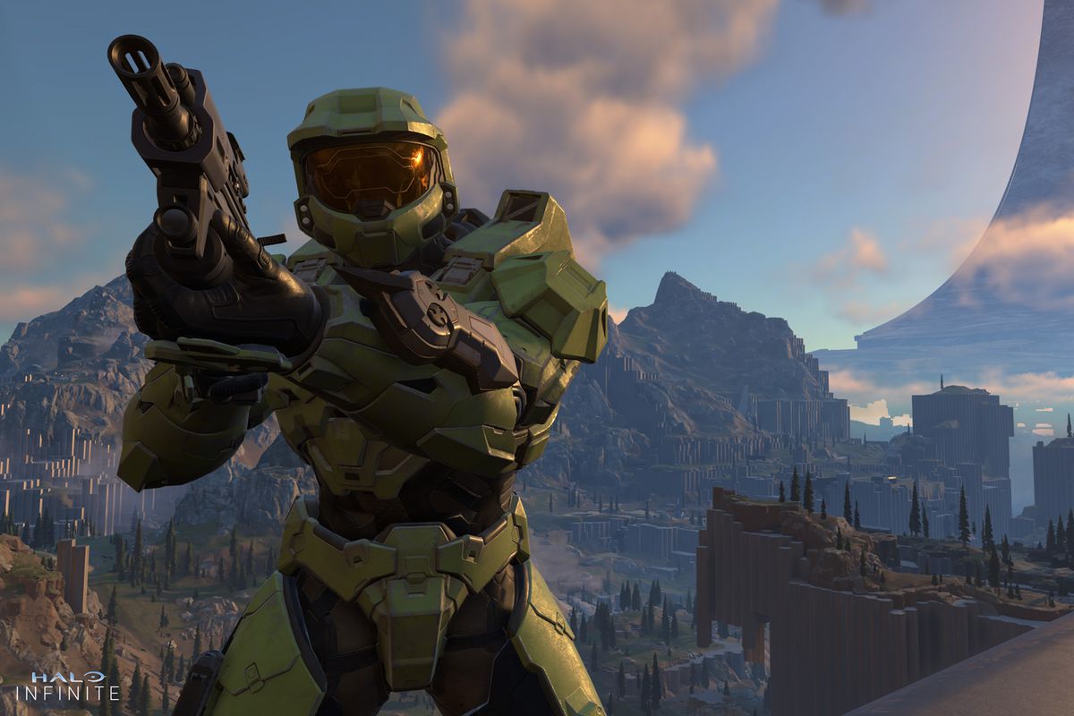 Master Chief aiming a gun while standing high up above a valley in Halo Infinite