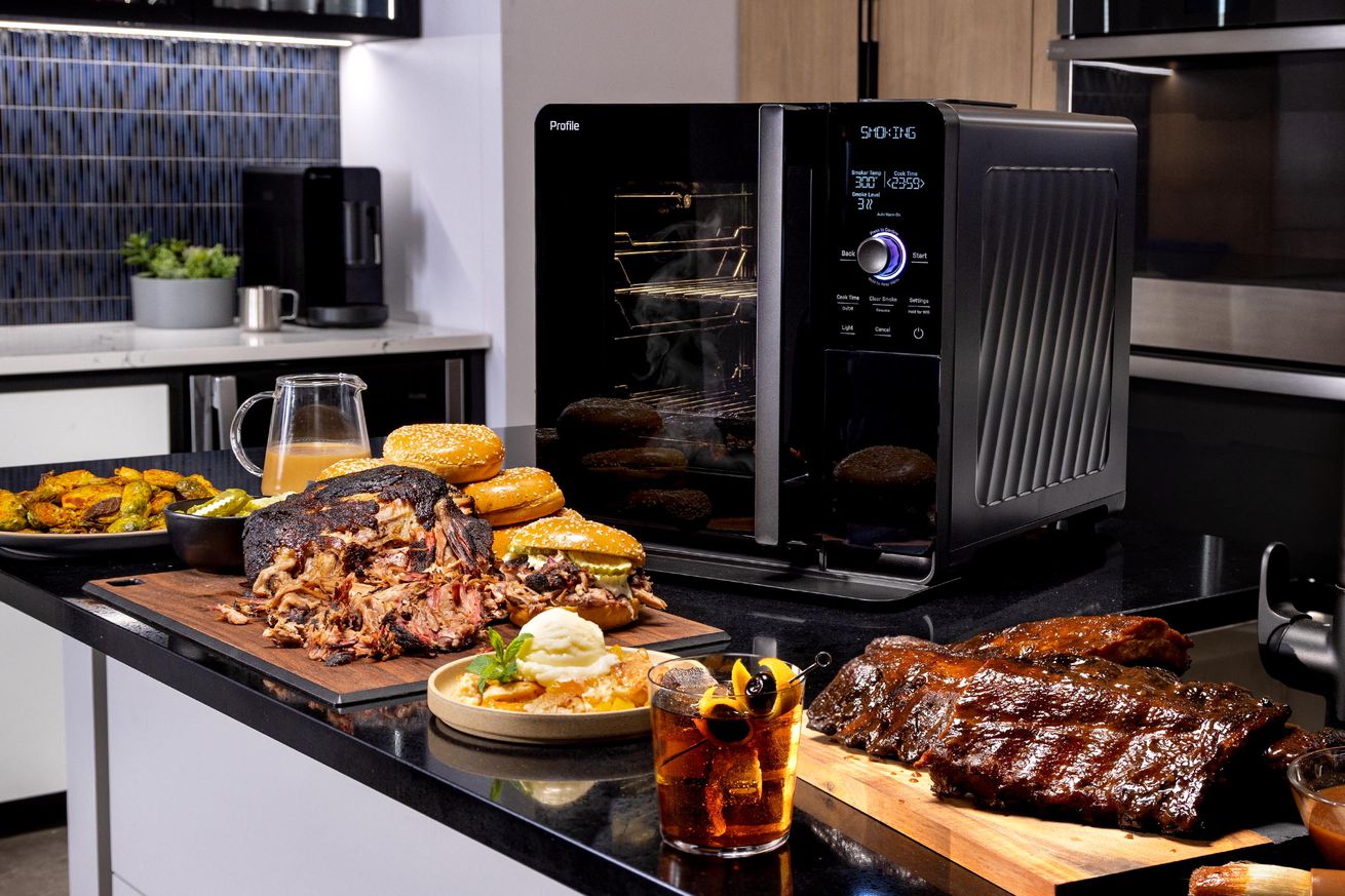 A black oven on a counter surrounded by smoked food.