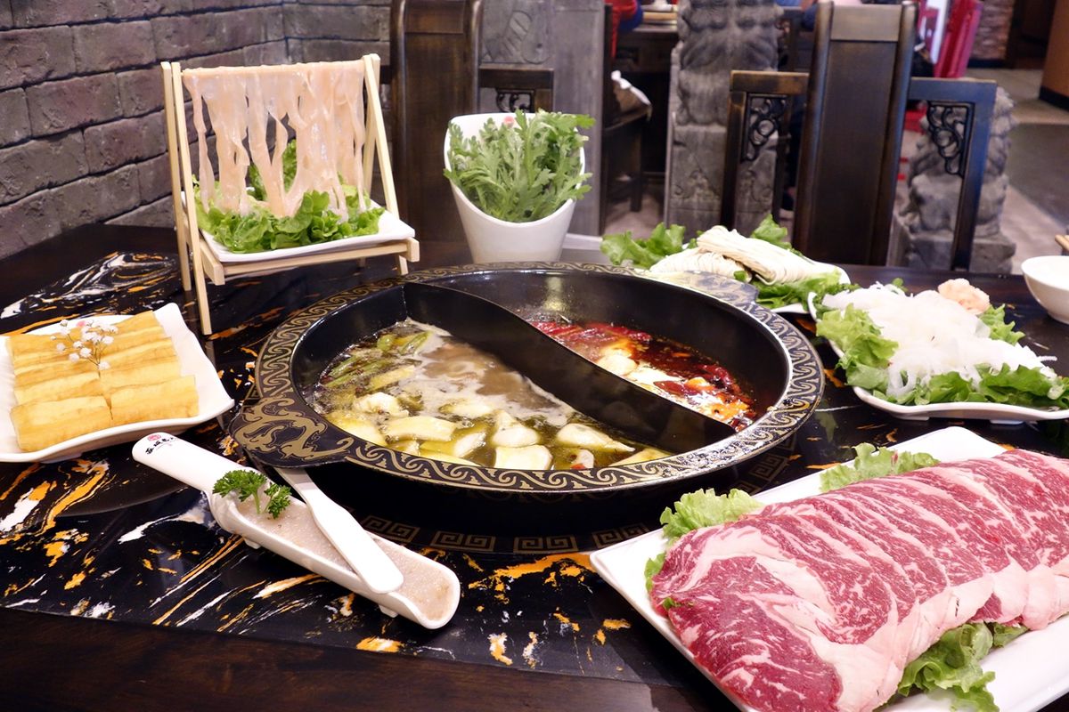 A stone hot pot near a side of raw meat at Chengdu Memory.